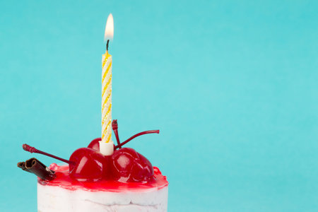 colorful cupcake with a cherry on top with a candle on a blue background, macroの写真素材