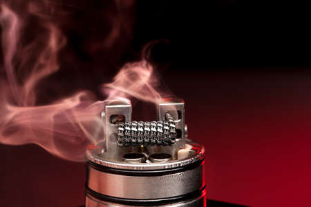 Applying liquid with nicotine in the coils on the RDA over the dark backgroundの写真素材