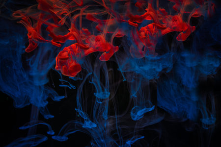 Color paint drops in water. Ink swirling underwater. Cloud of silky ink collision on black...