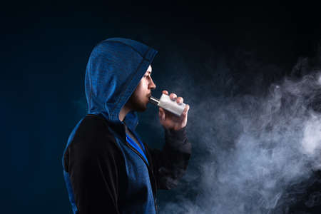 Vaping man. A cloud of vapor. dark blue background.の写真素材