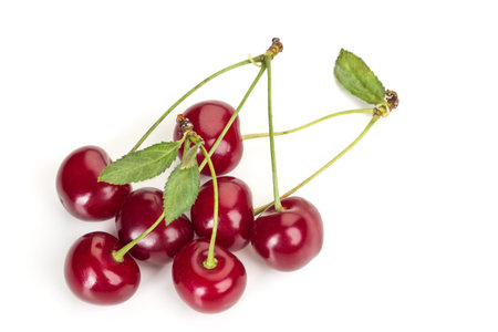 ripe juicy cherry berries with leaves on a white table on a white background