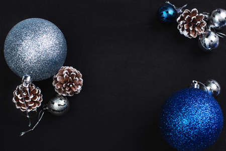fir cones and blue and silvery New Year balls on a black backgroundの写真素材