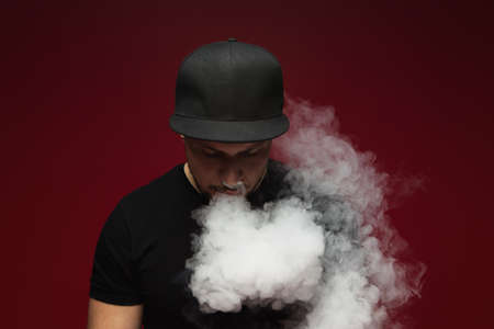 Vaping man. A cloud of vapor. red background.の写真素材