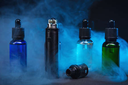 Photo for jars of liquids for vape in multi-colored smoke. dark background - Royalty Free Image