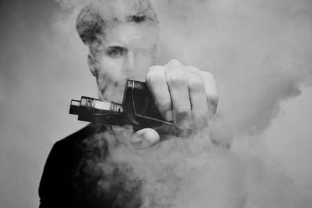Vaping man. A cloud of vapor. dark background. black and white photographyの写真素材