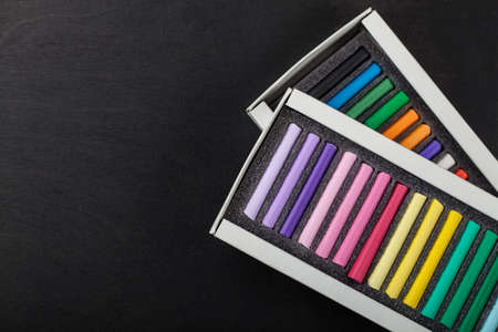 boxes with colored crayons pastels on a dark backgroundの写真素材