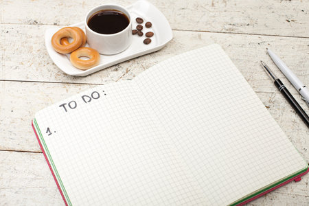 notebook with an inscription, coffee with bagels, pens and pencils on a wooden wooden background