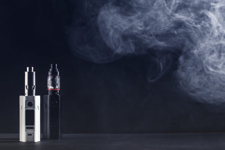 Electronic cigarette over a dark background. E-cigarette for vaping. Popular devices