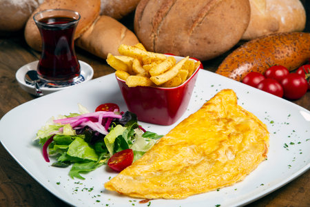 Omelet with french fries and salad on a wooden table.の写真素材