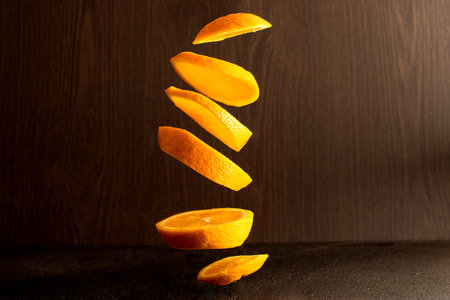 Falling slices of orange in air isolated on dark background