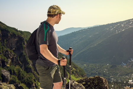 man walks in the mountains looking at the view from the height