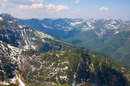 panorama of the green mountains in spring with snowy peaksの写真素材