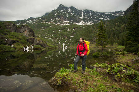 girl with backpack enjoying the view of a beautiful lake in the mountainsの写真素材