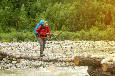 Man hiker walking across river in a forest, Europeの写真素材