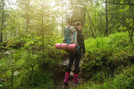 the girl with the backpack in the woods moving along a mountain pathの写真素材