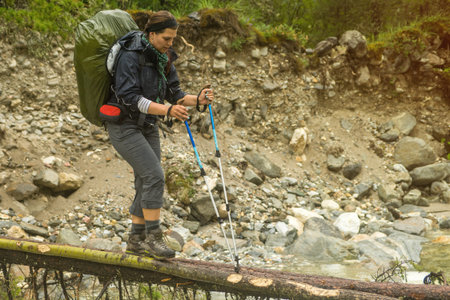 Woman hiker walking across river in a forest, Europe