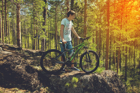 mountin biker with bike on the rocks. Successful happy rider on rocks holding bicycle. Sport,...