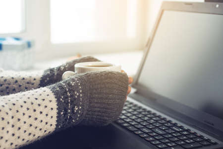 cropped view of the hands of a man is working at a laptop drinking coffeeの写真素材