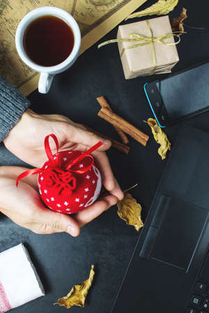 a man holds a gift with your hands in a sweater to warm up in front of a laptop, the concept of warm gifts, top viewの写真素材