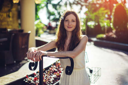 Woman relaxing and enjoying the warm sun in the Park standing with the iron bike. Travel concept.の写真素材