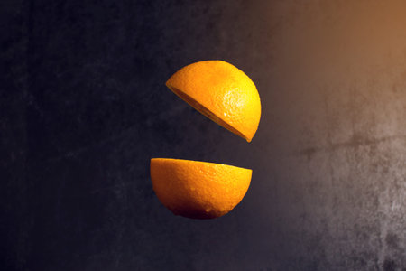 Orange cut in half are frozen in mid air on a black background, concept of healthy eatingの写真素材