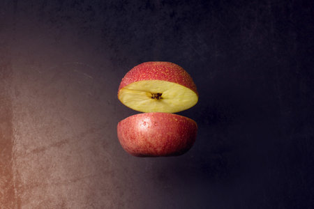 Apple cut in half are frozen in mid air on a black background, concept of healthy eating