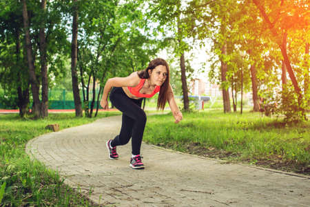 Ready steady go. Pleasant young lady on start position and going to run in park. Concept of a healthy lifestyleの写真素材