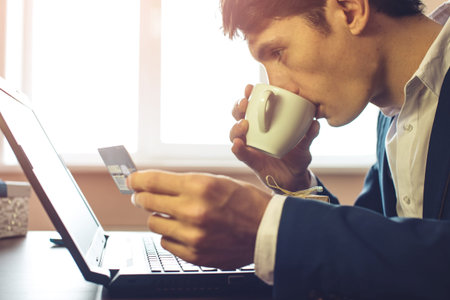 man businessman buying a gift online via credit card, close up view of his hands. the concept of...