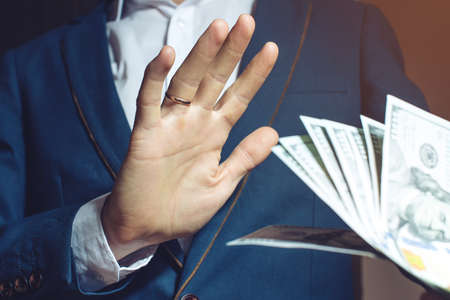 man businessman in suit refuses to take the bribe by showing that he was not corrupt. the concept of corruption and briberyの写真素材