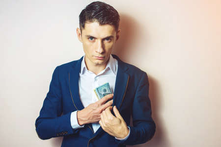 man businessman in suit taking notes, bills of dollars in his pocket as a bribe. the concept of corruption and briberyの写真素材