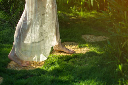 girl walking barefoot on the stones in heart shape on green grass, concept of love for the natureの写真素材