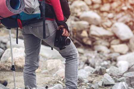 Hipster girl with backpack in the mountains holding the camera in hand, the concept of travel, active rest on the natureの写真素材