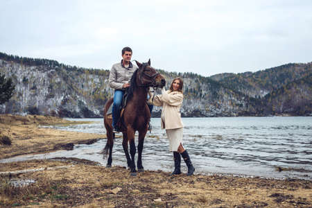 pregnant girl and her husband standing next to the horse near the riverの写真素材