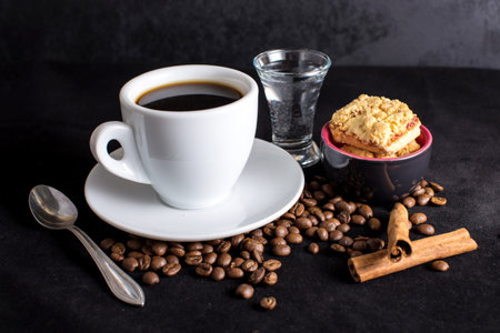 Cup of black coffee with biscuits, cinnamon, dark backdrop