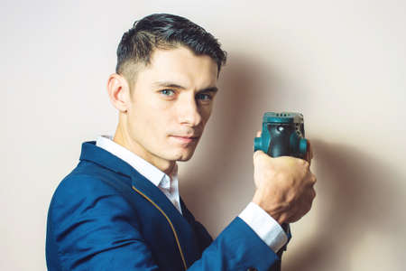 young man in suit holds in hand a power drill and works with it, a businessman for dirty workの写真素材