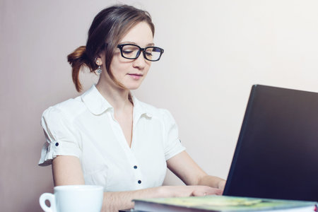 attractive girl with the glasses typing on a laptop working in office. business woman lady