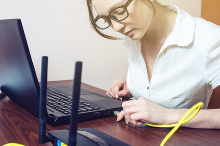 woman working in the office trying to connect the Internet cable to the connector on the laptop for a good Internet connection. the concept of wired and wirelessの写真素材