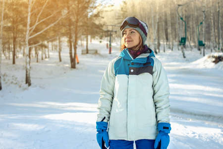 woman snowboarder on the mountain is downhill among the trees at sunset, concept of sport and active lifestyleの写真素材