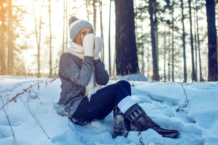 attractive woman in winter, a knitted sweater, mittens and scarf, walking through the Park among the...