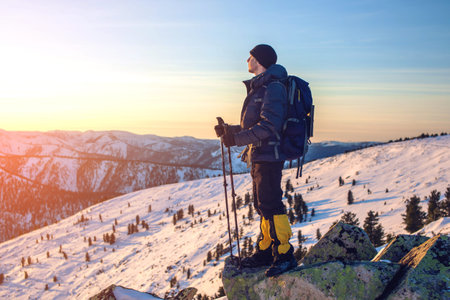 man tourist hikers standing on snowy mountain on the way to the top at sunset, the concept of the path to purpose and successの写真素材