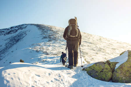 tourists hikers traveling on the snowy mountains to the top at sunset, the concept of the path to purpose and successの写真素材