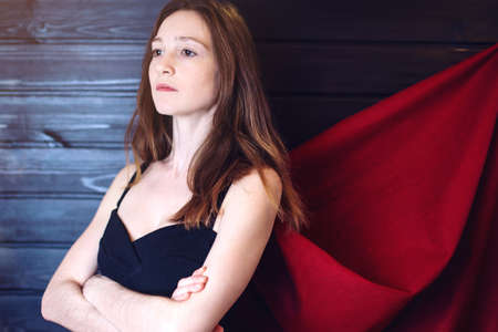 Superwoman. Attractive woman office worker standing in a suit and red cloak like a superhero. the concept of progress in your careerの写真素材