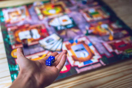 Hand throws the dice on the background of colorful blurred fantasy Board games, gaming moments in dynamicsの写真素材