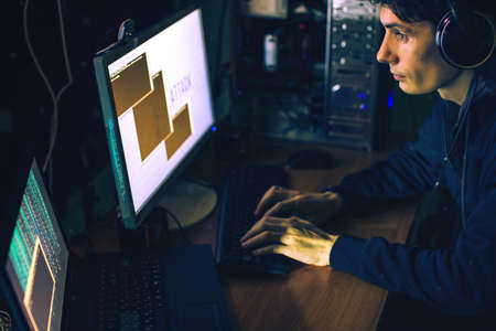 young hacker in the dark breaks the access to steal information and infect computers and systems. concept of hacking and cyber terrorismの写真素材