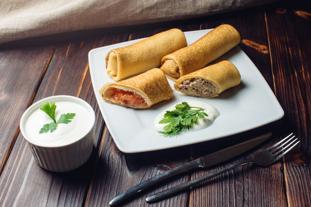 Pancake rolls with meat and fish salmon. Beautiful table setting with parsley, dill and sour cream....