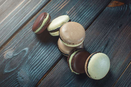 Coffee and chocolate macarons with vanilla cream on a dark wooden table. French dessertsの写真素材
