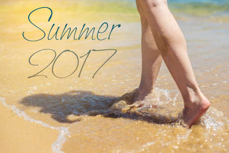 Woman walks barefoot in the sand washed by sea wave on the beach. Summer 2017, Paradiseの写真素材