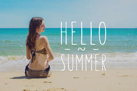 Woman in swimsuit sitting on the sandy beach and looks out to sea. The summer time. The concept of a Paradise vacationの写真素材