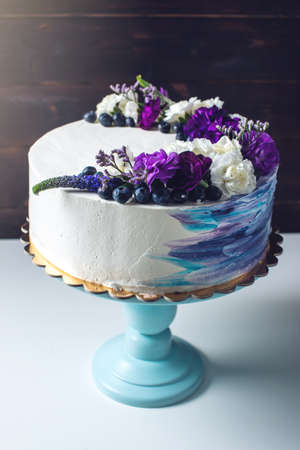 Colorful wedding cream cake with lovely purple flowers adorn the top and blueberriesの写真素材