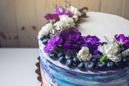 Colorful wedding cream cake with lovely purple flowers adorn the top and blueberriesの写真素材